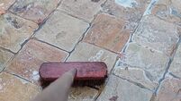 Cleaning and scrubbing sandstone pavement of a terrace with a brush