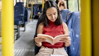 Young woman reading a book while commuting by bus