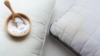 White pillow with yellow saliva stains and baking soda (sodium bicarbonate) on white background. baking soda to clean their dirt