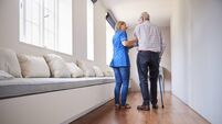 Nurse helping senior man walk using a walking stick