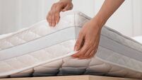Woman putting soft white mattress on bed indoors, closeup