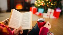 Woman reading a book and drinking coffee at christmas