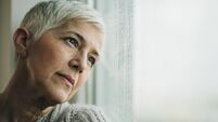 Pensive mature woman day dreaming by the window.