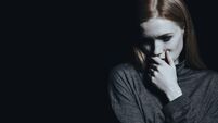 Sad girl against black wall