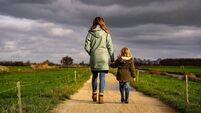 Rear View Of Mother And Daughter Walking On Road Against Sky
