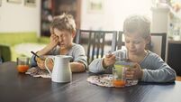 Sleepy little boys eating breakfast cereal