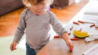 Child drawing on a table at home and making a mischief