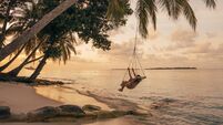Young adult woman relaxing on a swing in a tropical paradise