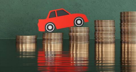 Red paper cutout car on stacks of gold coins on green background. Illustration of the concept of increasing car prices, surging