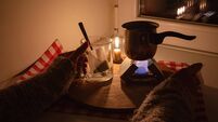 A woman boils water for tea on a small tourist stove with dry fuel in complete darkness during a power and gas outage at home. B