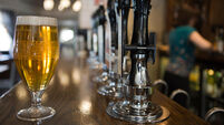 A pint of lager in a pub with a member of staff behind the bar