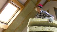 Man installing thermal roof insulation layer - using mineral wool panels. Attic renovation and insulation concept