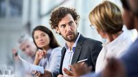 Male entrepreneur talking about reports with his colleagues on a meeting.
