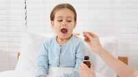 Mother giving cough syrup to her daughter in bedroom
