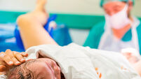 Cute newborn baby boy just after childbirth and doctor in the background