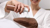 Self-tanning. Woman applying cosmetic product onto tanning mitt indoors, closeup