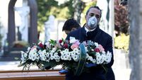 FILE PHOTO: Cemetery workers and funeral agency workers in protective masks transport a coffin of a person who died from coronav