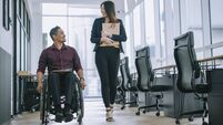 Indian white collar male worker in wheelchair having cheerful discussion conversation with his female asain chinese colleague co