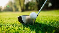 Golf club and golf ball on a green lawn in a beautiful golf course - Stock Photo