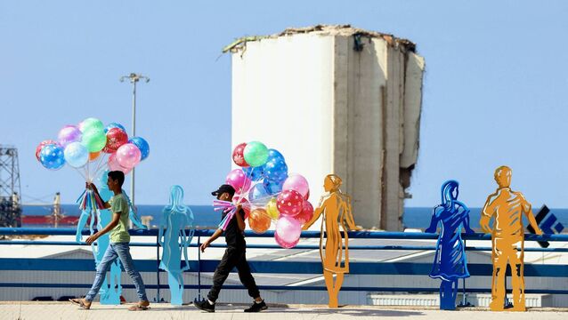 <p>Young street vendors selling balloons walk past sculpted figures representing people staring at the devastation on a sidewalk overlooking the port of Beirut on August 4, 2024. Picture: Ibrahim Amro/ AFP</p>
