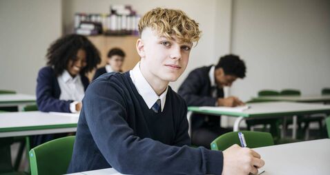 Portrait of British secondary schoolboy taking exam
