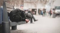 Poor homeless man or refugee sleeping on the wooden bench on the urban street in the city, social documentary concept, selective