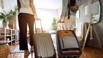 Unrecognizable couple arriving at the accommodation with their suitcases