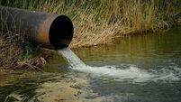 Draining sewage from pipe into river, pollution rivers and ecology.