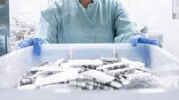 Pharmaceutical employee seen holding a box with numerous blister packs in a special room
